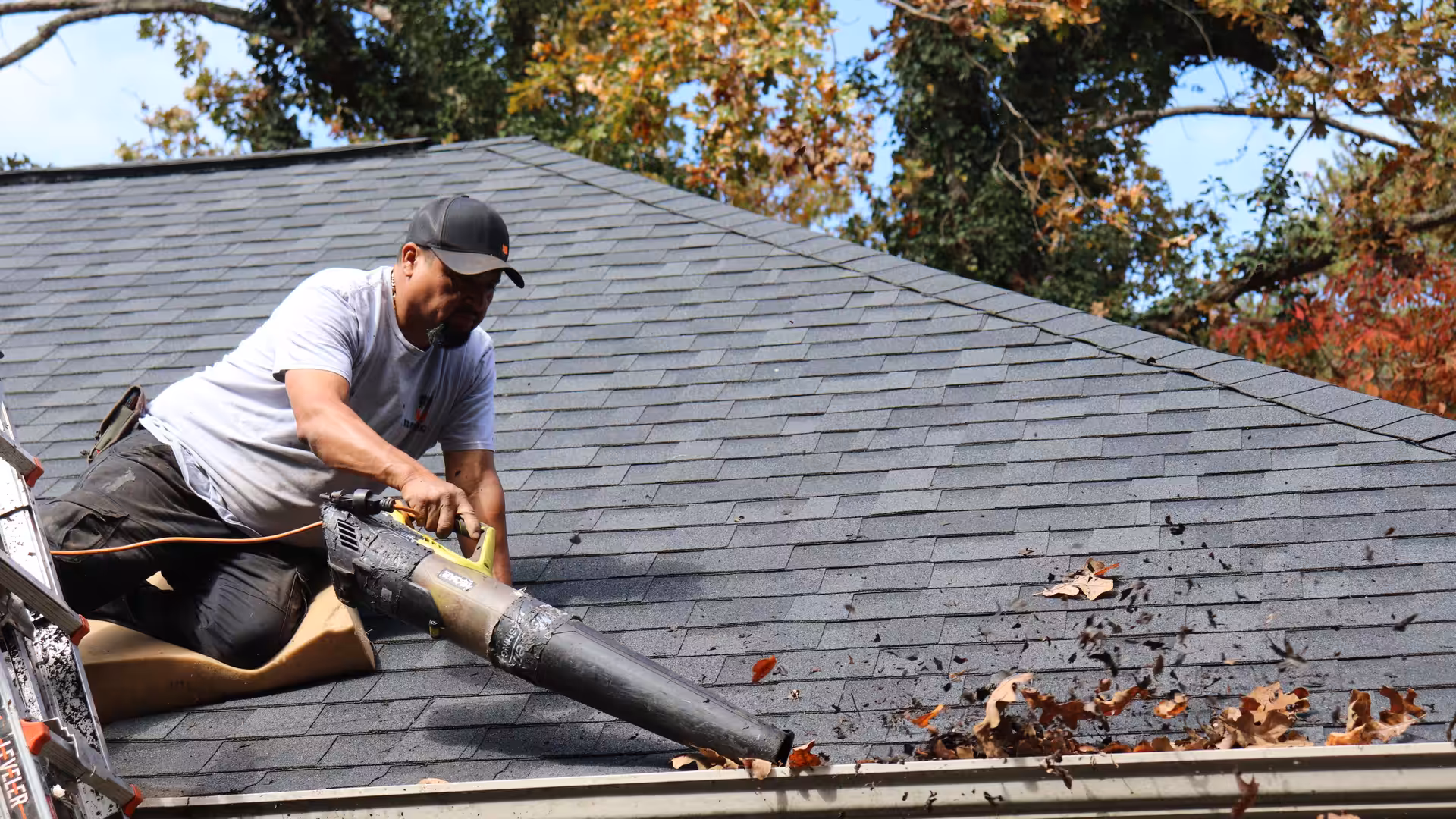 MBA Roofing technician clearing leaves from a roof and gutters in North Carolina