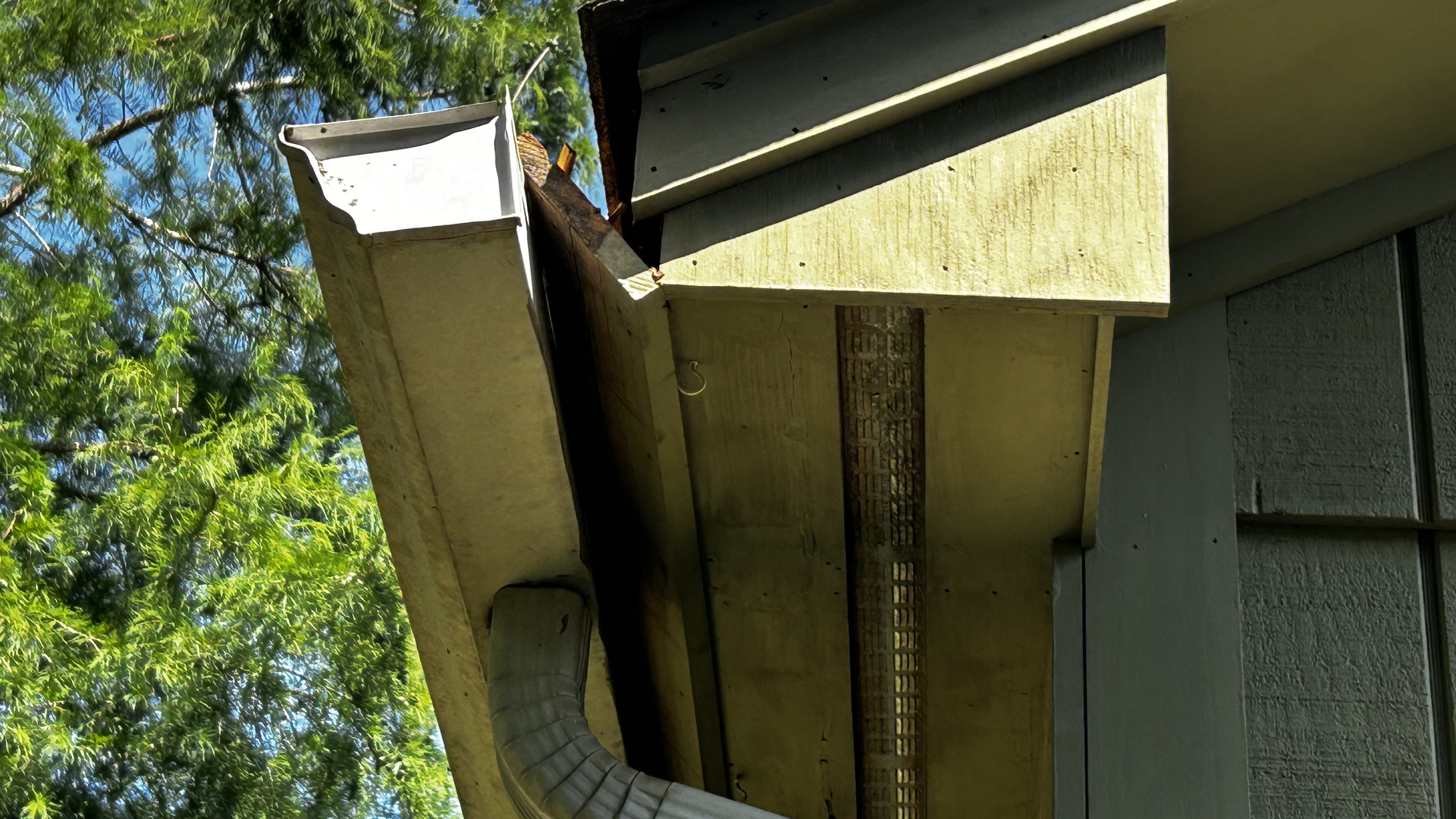 Storm-damaged gutter and fascia pulled away from a North Carolina home